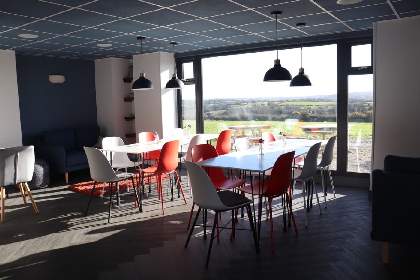 Tables laid in the café, with the long window and the fields beyond it
